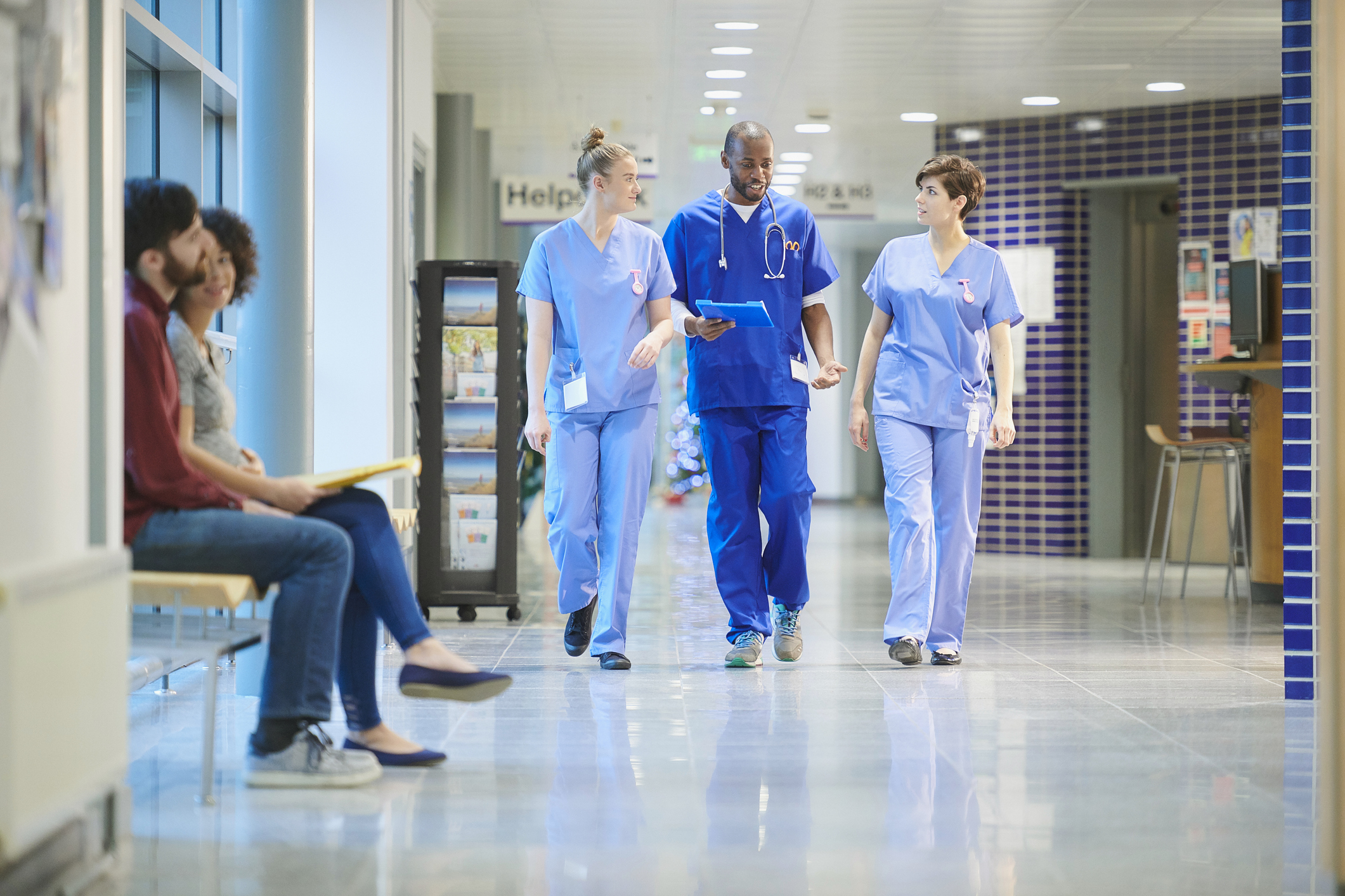 A doctor and two assisting clinical staff in uniform in hospital hallway