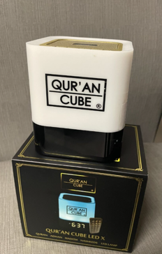 White and black Qur’an Cube LED device displayed on its branded box, showing digital time and controls.