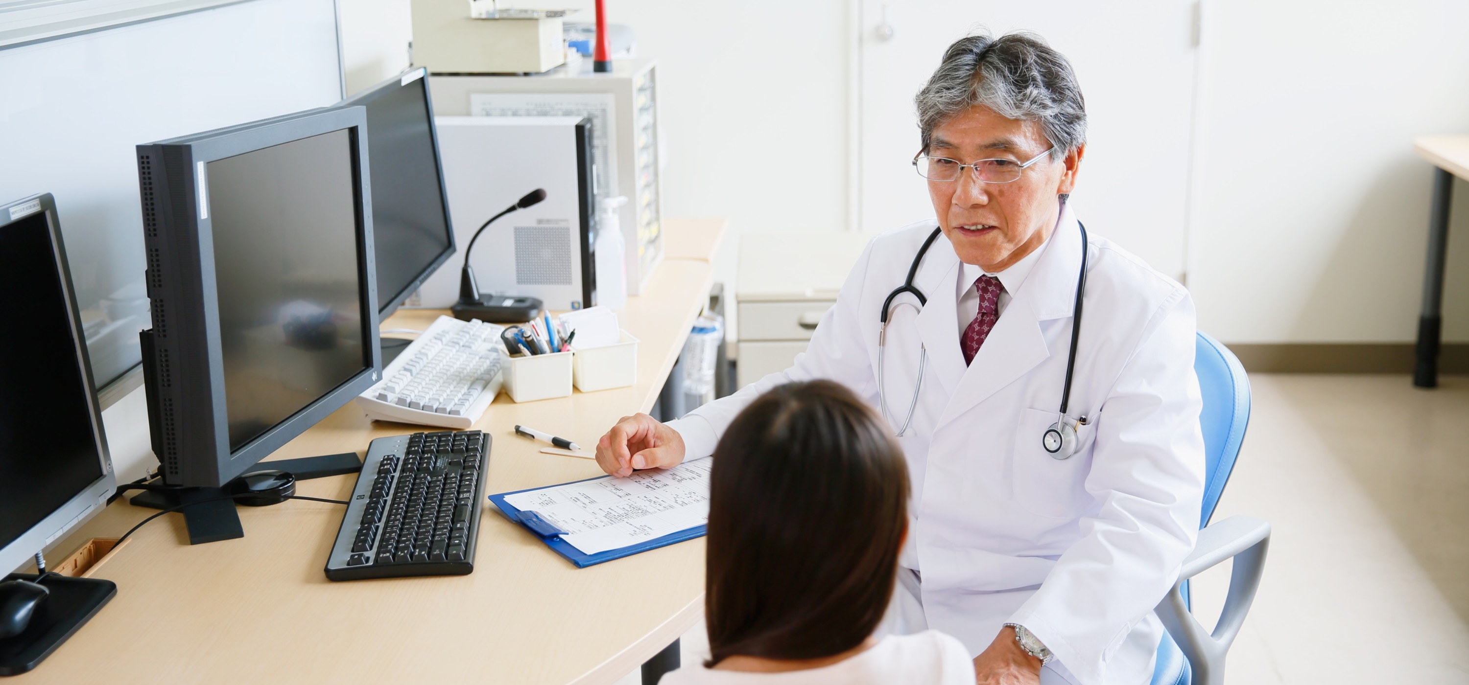 A physician speaking to a patient at his desk.