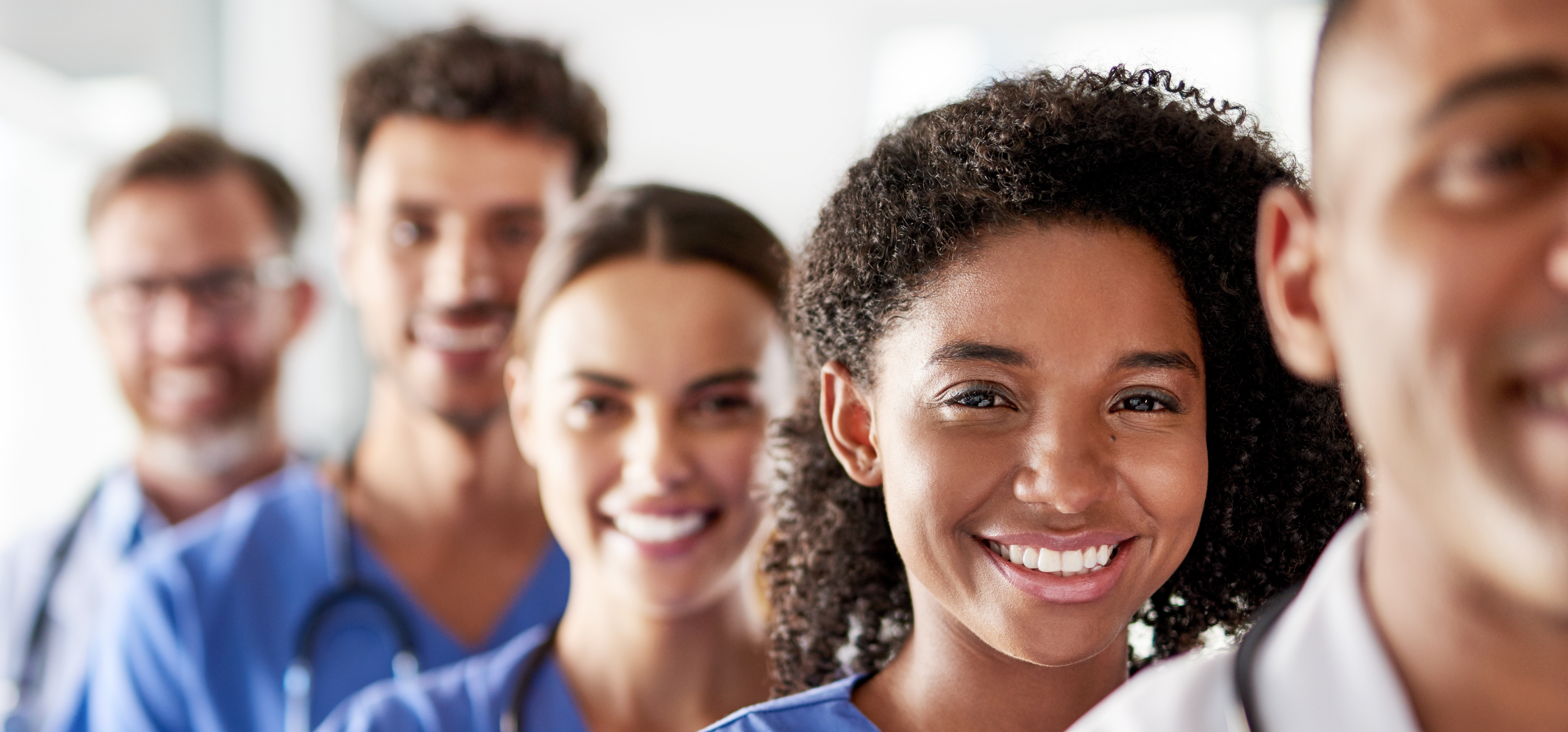 Five healthcare professionals lined up together in formal clinical setting