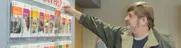Man selecting book from medical journals rack, symbolizing access to health resources.