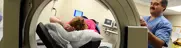 Nuclear medicine procedure, patient lying inside machine while one staff assists