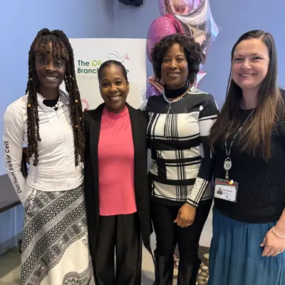 Photo of four women standing and smiling at the camera.