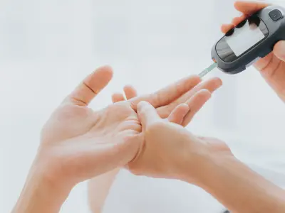 The hands of a health-care provider checking the blood sugar of a patient.