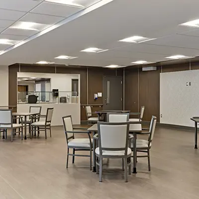 Dining and Activity Space with 3 tables in picture surrounded by chairs in a large dining hall
