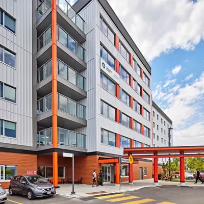 Side view of hospital exterior with emergency vehicles and other cars parked outside