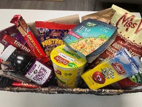 Basket filled with packaged kosher snacks, including chips, crackers, and bottled drinks.