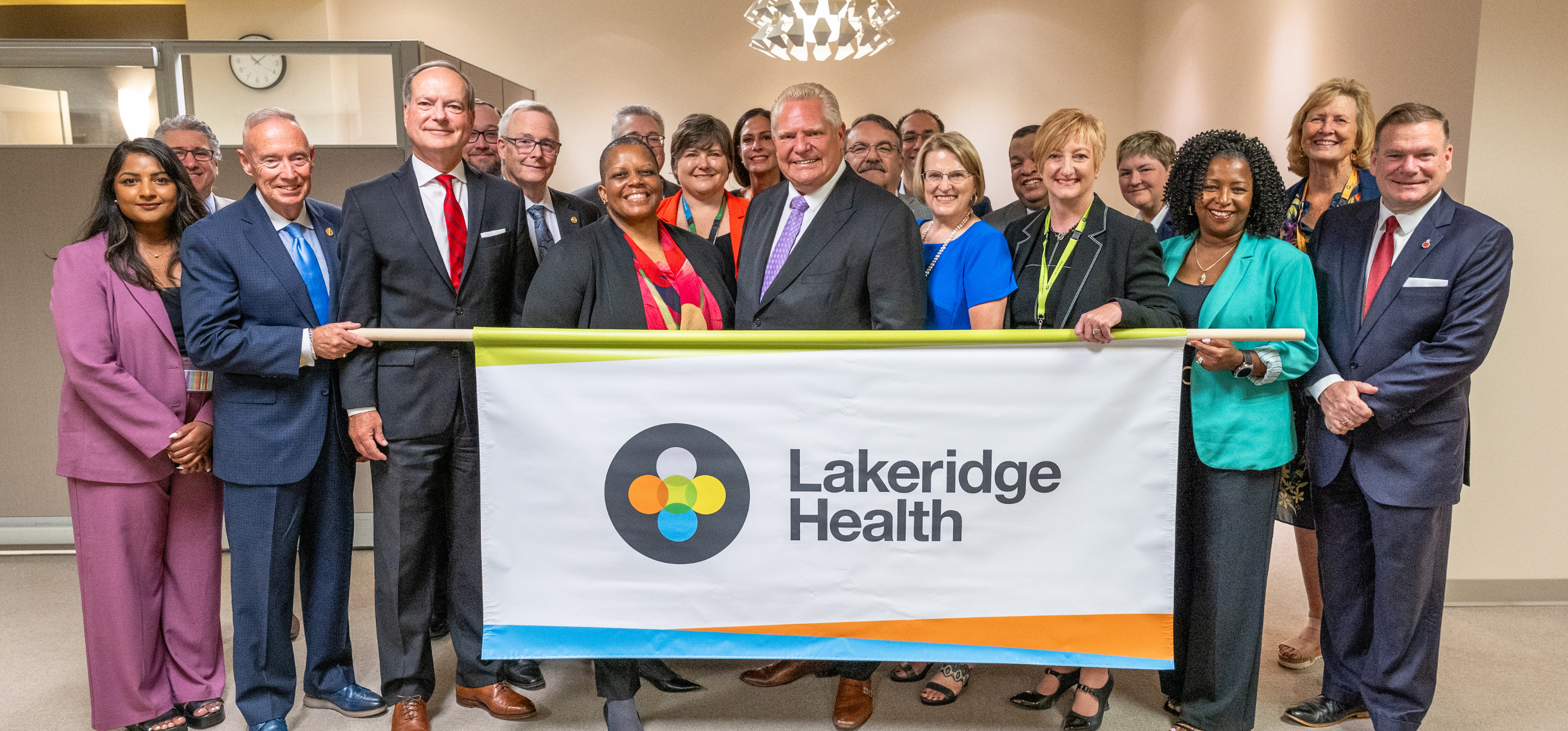 Premier announcement image with Lakeridge poster held by medical chiefs and leadership team